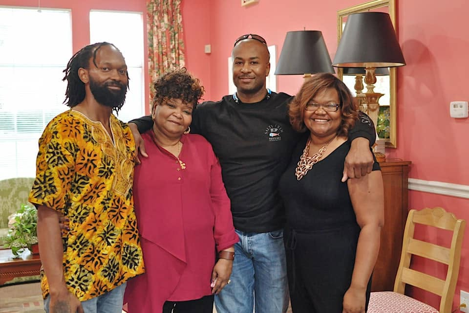 Four family members posing together in a warm home setting